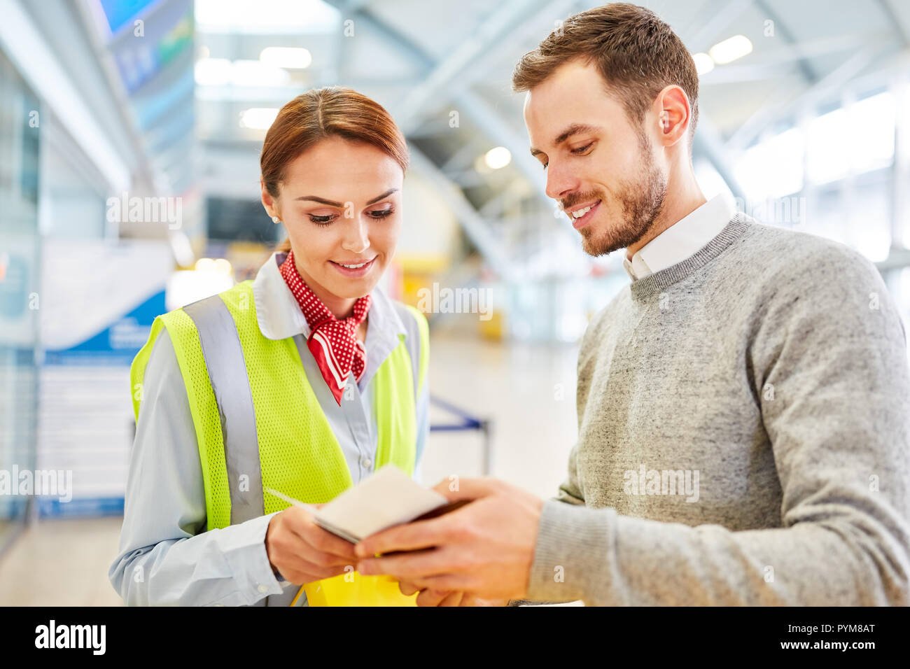 empleado de servicio en el mostrador de check in del aeropuerto controla el pasaporte del hombre como un pasajero pym8at